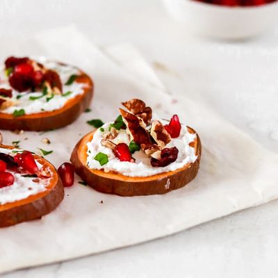 Sweet potato rounds topped with creamy cheese, walnuts, pomegranate seeds, and herbs.