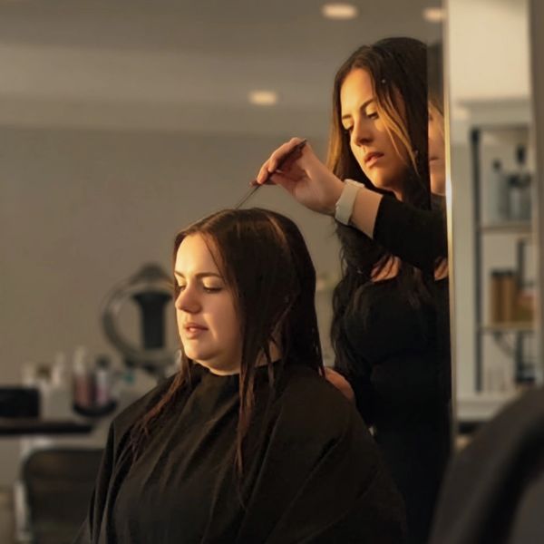 A hairdresser styling a woman's hair in a salon.