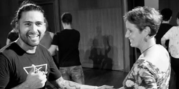 Two people smiling and dancing together indoors.