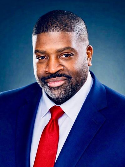 Professional man in a blue suit and red tie smiling confidently.
