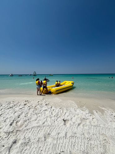 People in life jackets preparing a yellow inflatable boat at the beach.