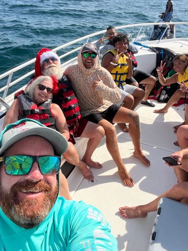 Group of friends having fun on a boat with one person wearing a Santa hat.
