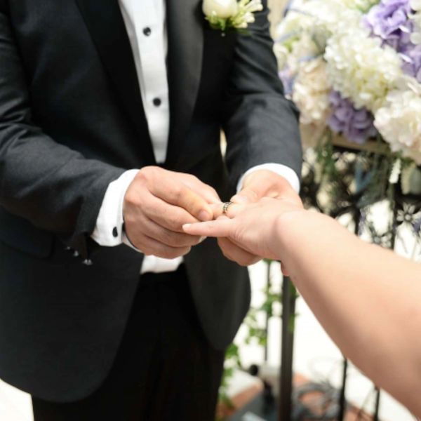 Groom placing ring on brides finger during wedding ceremony