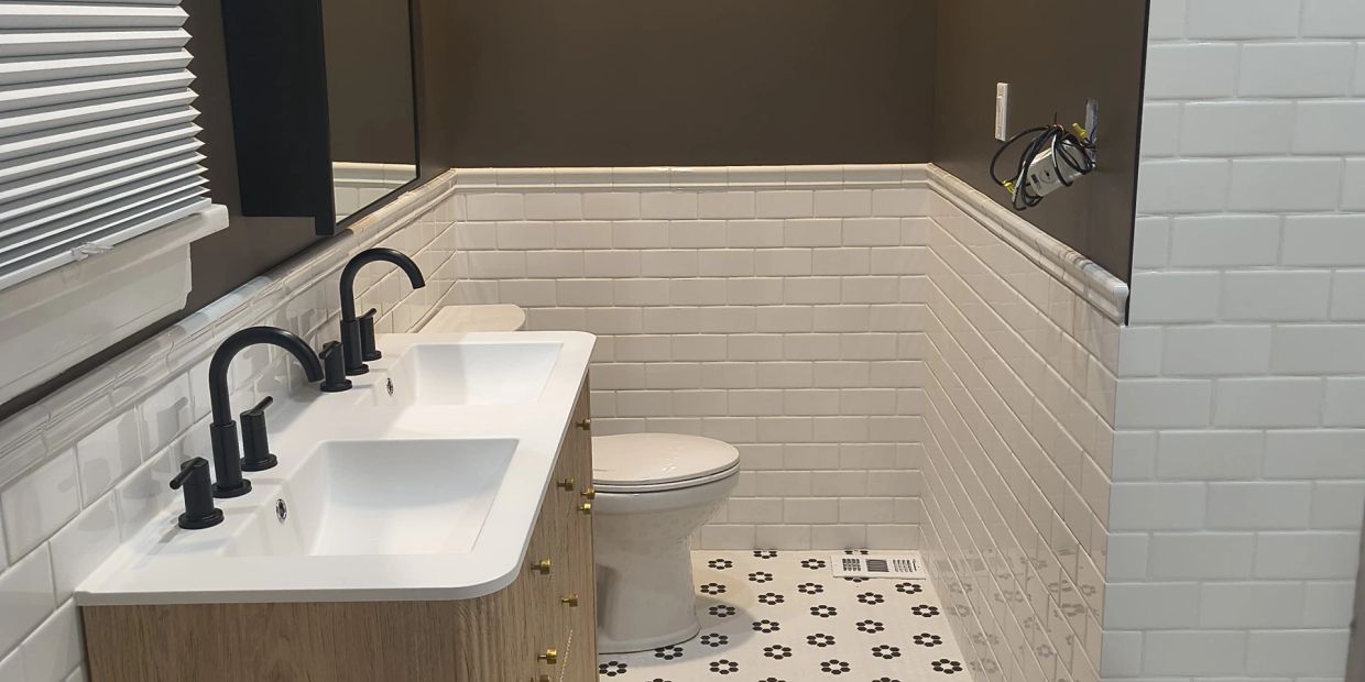 Modern bathroom with double sinks, black fixtures, and patterned floor tiles.