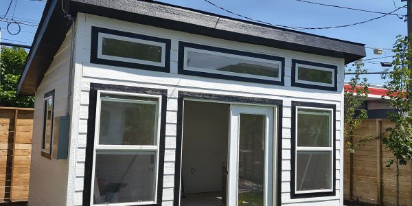 Newly built small white house with black trim and sliding glass door.