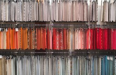 A picture of fabric swatches hanging in a uniformed fashion in a retail display.
