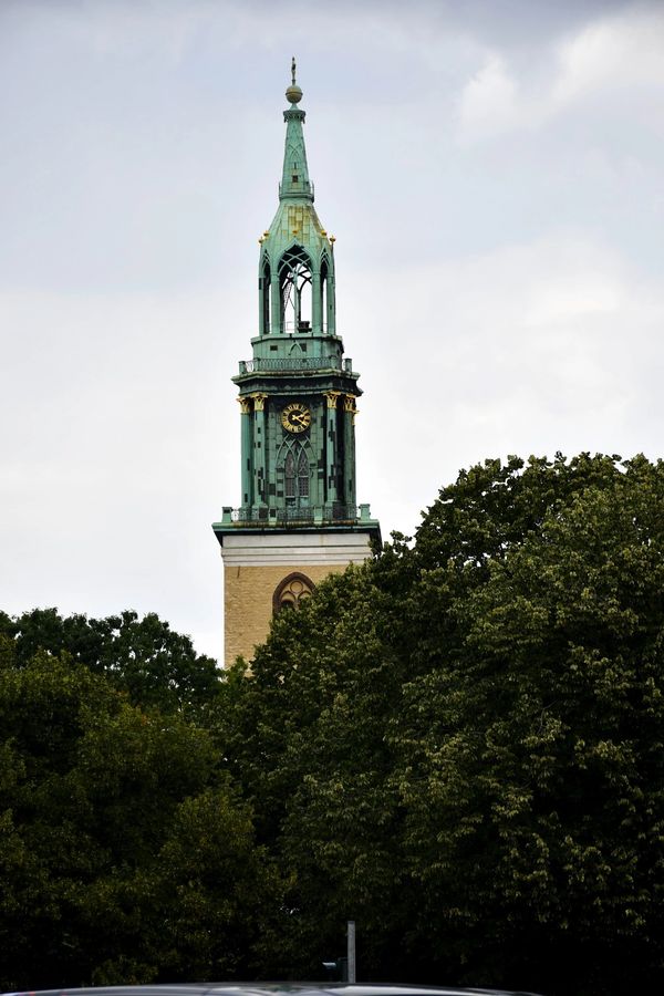 Church bell tower through trees in Germany.