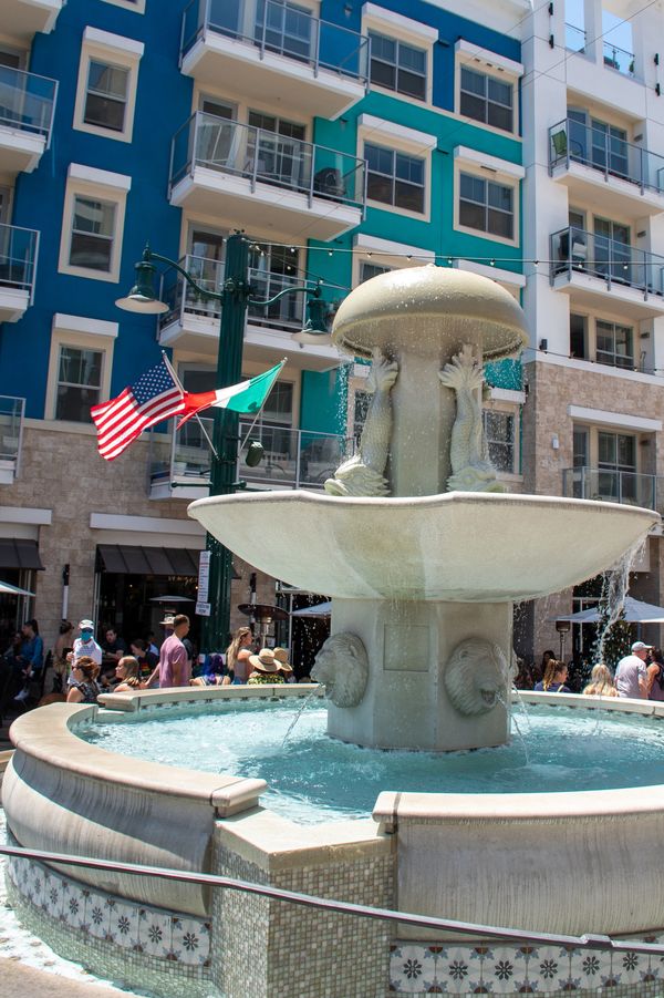 White stone fountain in San Diego in front of bright blue apartments.
