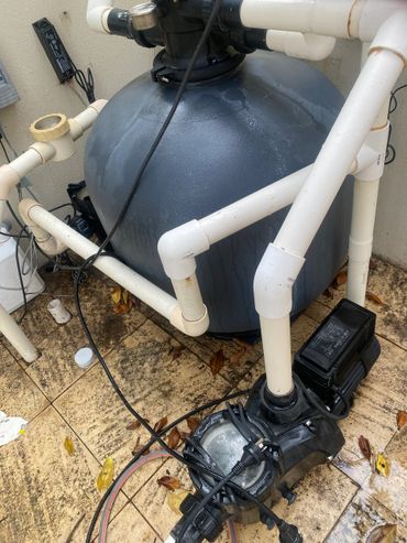 Pool pump system with pipes and electrical connections on tiled floor.