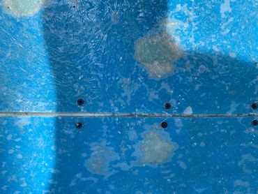 Worn blue surface with screws and shadow patterns.