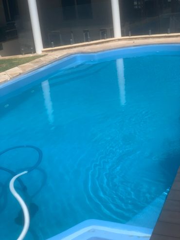 Clear blue swimming pool with cleaning equipment inside.