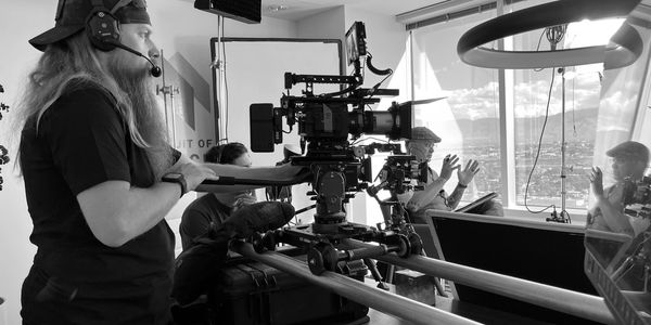 Film crew operating camera indoors near window.