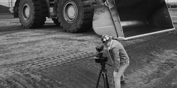 Person filming near large construction vehicle.