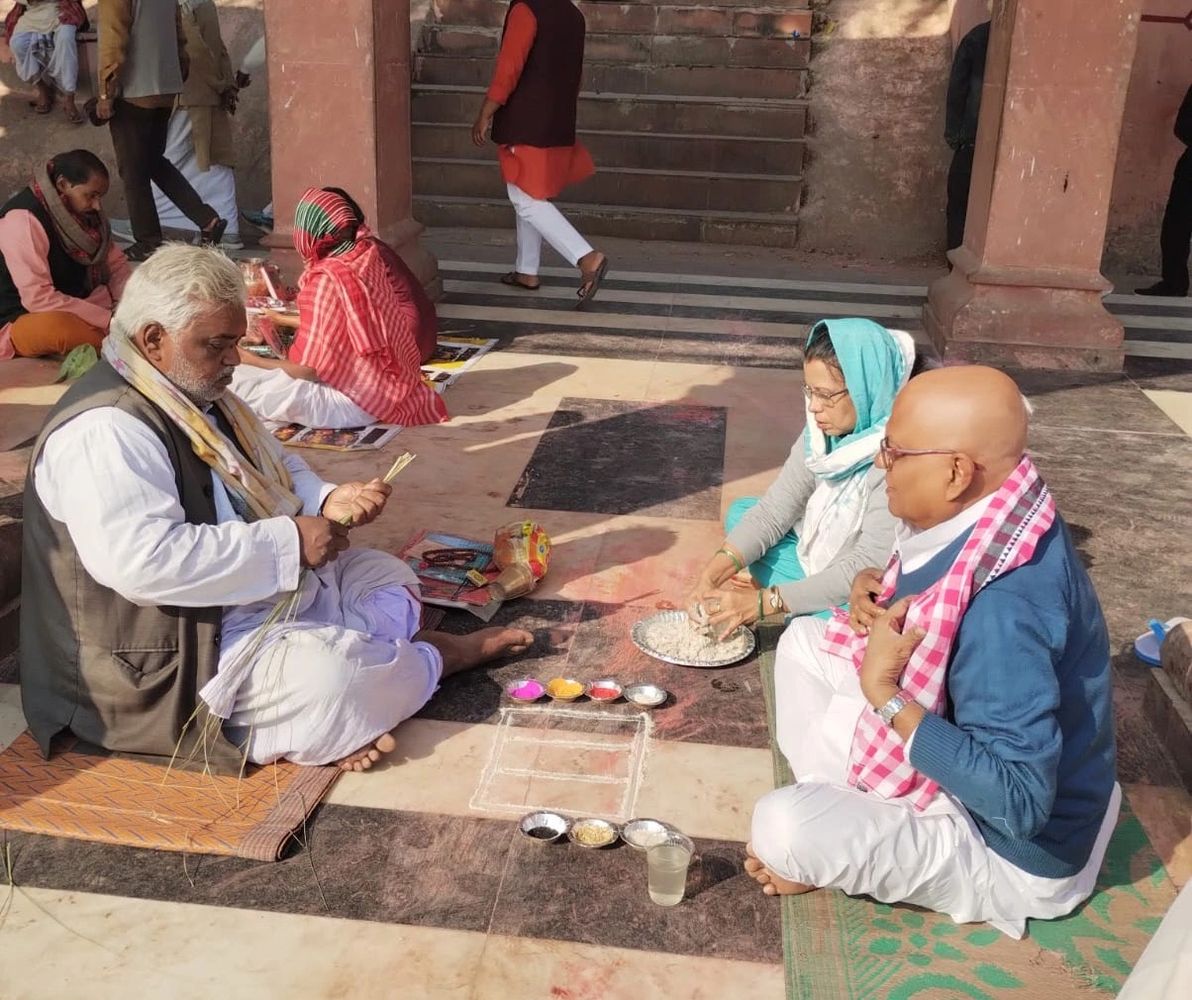 People sitting on the floor preparing for a traditional ritual with colored powders and offerings.