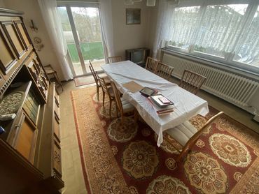 Möbliertes Esszimmer mit Tisch, Stühlen, Teppich, Schrank und Fernseher vor der Haushaltsauflösung