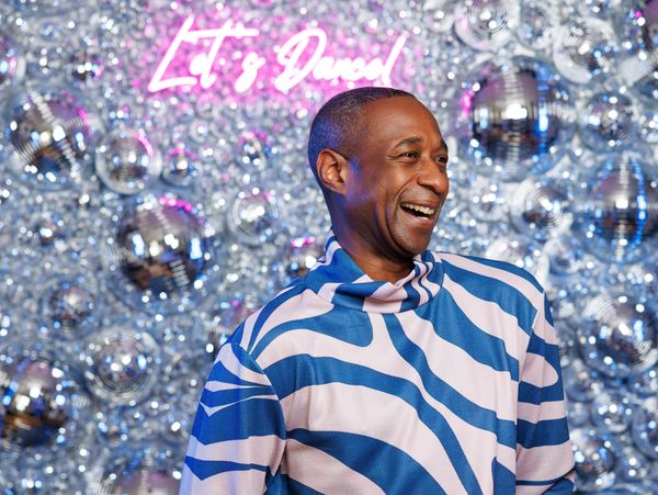 Man smiling in front of disco balls and 'Let's Dance' sign.