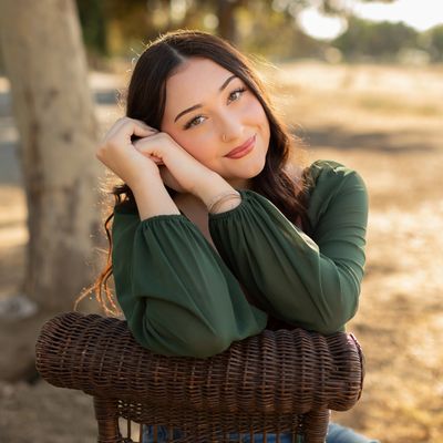 Young woman smiling while resting on a wicker chair.