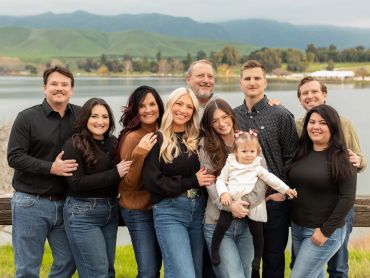A happy family posing outdoors near a lake.