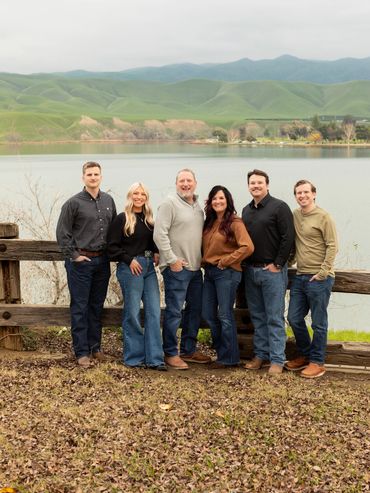 Family posing by a lakeside with hills in the background.