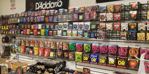 Wall display of various guitar strings and accessories in our music store.
