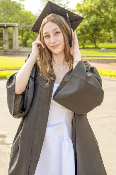 Young woman in graduation gown and cap outdoors.