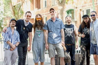Group of seven casually dressed men posing outdoors.