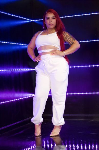 Woman with red hair in white outfit and clear heels.