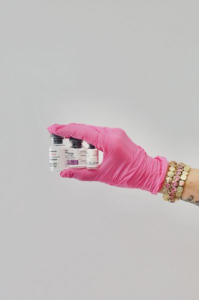 Hand in pink glove holding vaccine vials.
