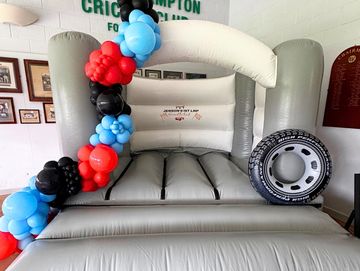Inflatable grey couch with colorful balloon decoration.