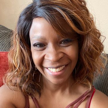 Smiling woman with wavy hair sitting on a couch.