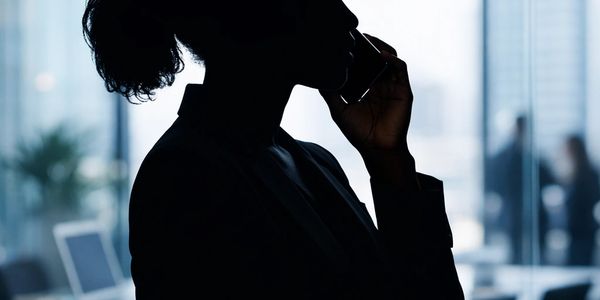 Silhouette of a woman talking on the phone in an office setting.