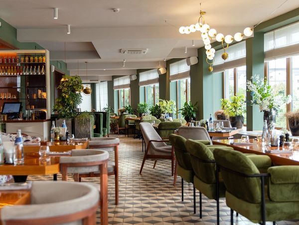 Bright, modern restaurant with green and beige seating and large windows.