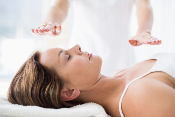 Woman laying down with her eyes closed receiving Reiki healing.