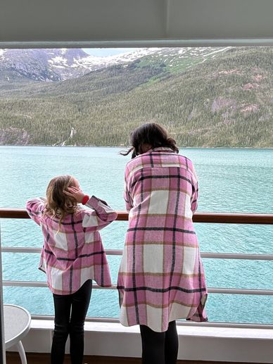 Stephanie and Emily in matching pink plaid jackets overlooking water and mountains.