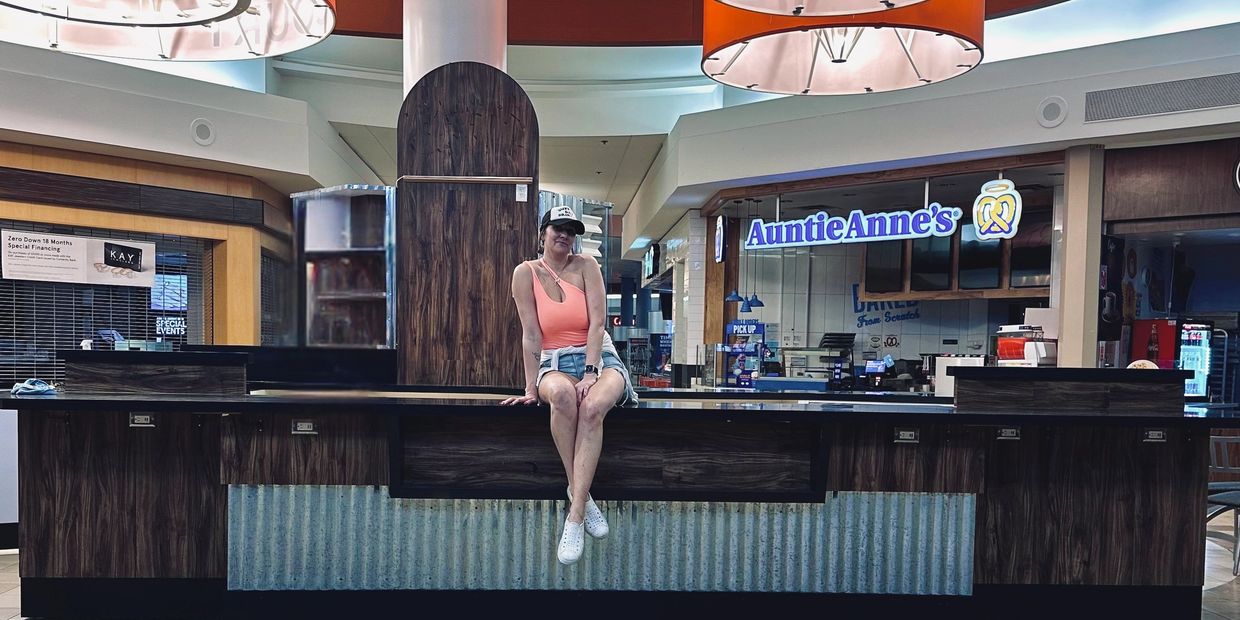 Stephanie Nicole sitting on the empty bar counter at Caps & Corks, reflecting on small business owne