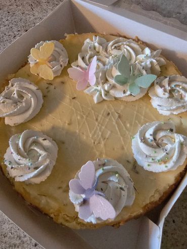 Cheesecake decorated with whipped cream and pastel butterflies.