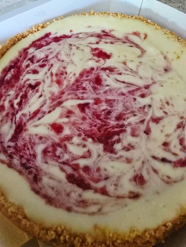 Close-up of a creamy raspberry swirl cheesecake with a crumbly crust.