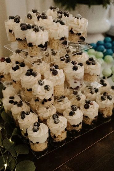 Mini blueberry cheesecakes in clear cups on a tiered stand.