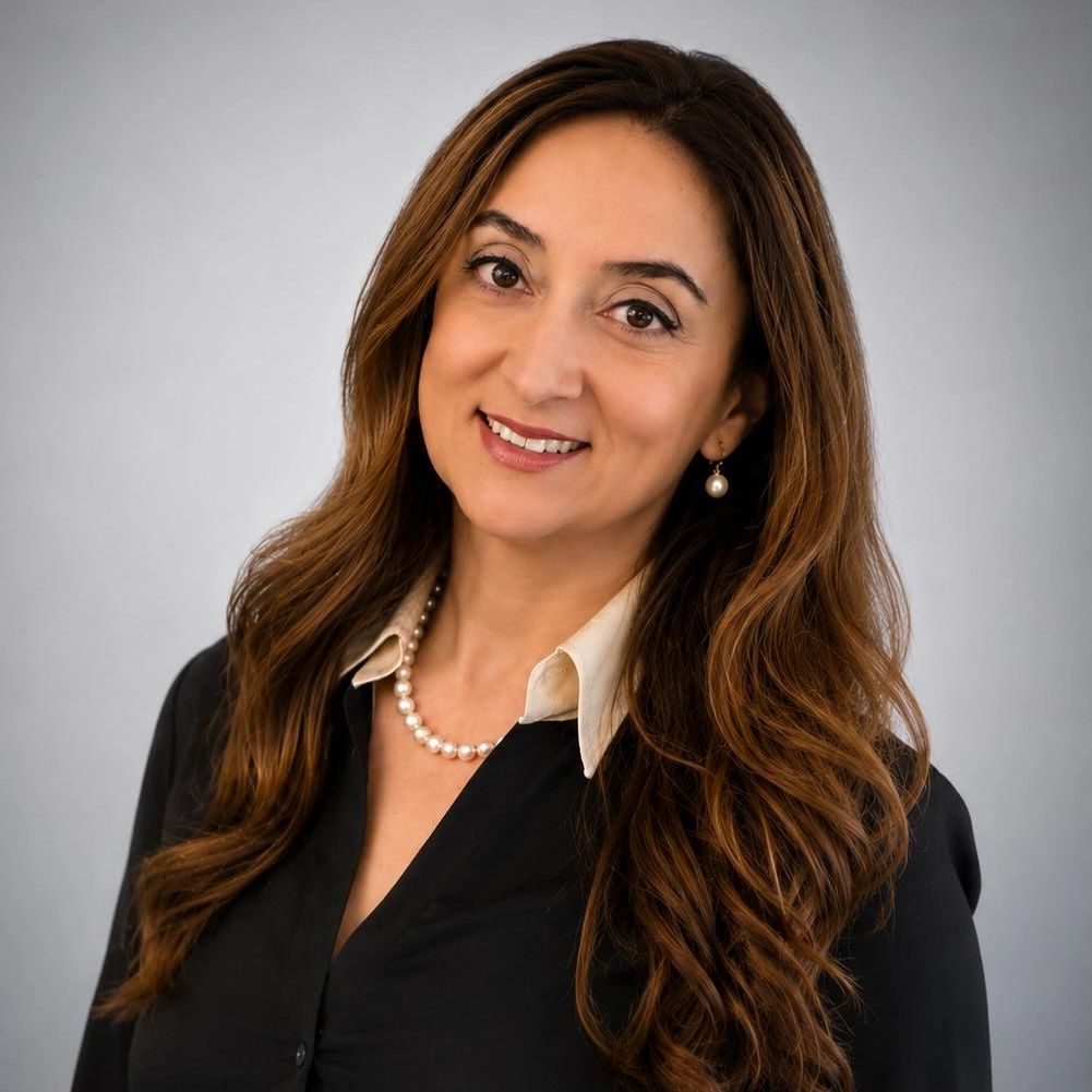 Professional woman with long brown hair wearing a black blouse and pearl necklace.