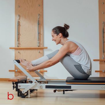 Woman doing Pilates on a reformer machine in a studio.
