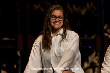 A Sing-Out cast members smiles from the stage.