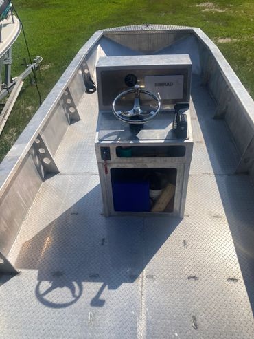 Aluminum fishing boat with steering console and storage space.