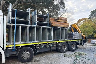 Flatbed truck loaded with metal scaffolding and wooden planks.