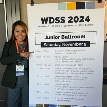 Woman standing by event banner.