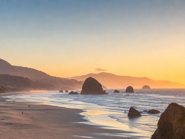 Sunset over a rocky beach with mountains in the background.