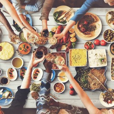 Friends clinking glasses over a table filled with diverse dishes.