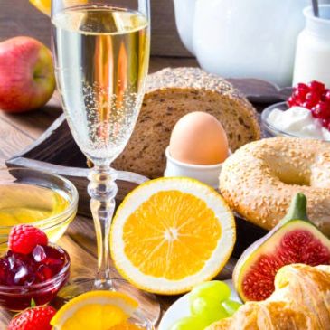A colorful breakfast spread with fruits, bread, and a glass of sparkling drink.