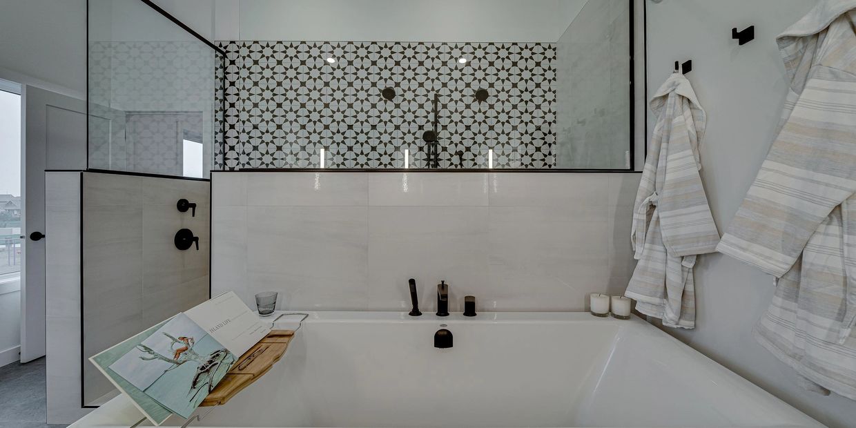 Beautiful black and white tiled shower in front of free-standing tub.