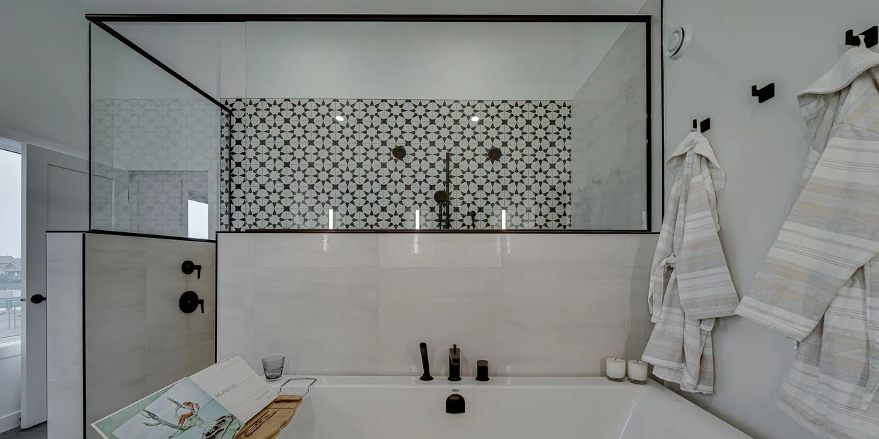 Beautiful black and white tiled shower in front of free-standing tub.