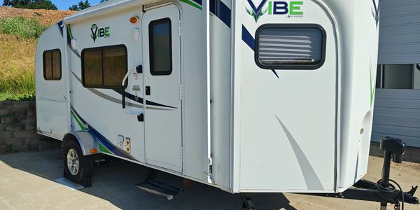 White and green Vibe travel trailer parked on a driveway.